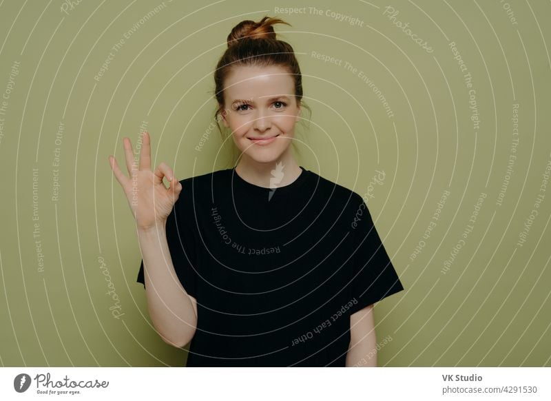 Calm brunette woman in black tee shirt showing okay sign happy young gesture girl pose smile background hand person female beautiful teenager portrait pretty