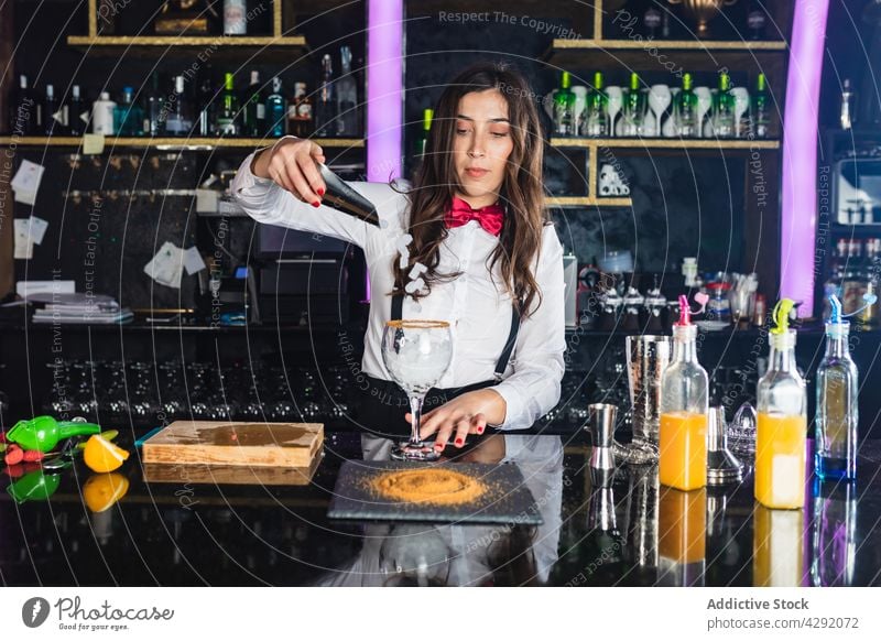 Stylish woman preparing alcoholic cocktail in modern bar prepare drink barkeeper female ice cube beverage shaker nightclub barmaid mixing trendy decorate lemon