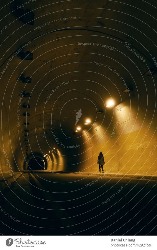 Girl Walking In The Night Tunnel Alone night dark contrast light road street Street lighting girl one person Dark Light Evening Night shot Lighting mood moody