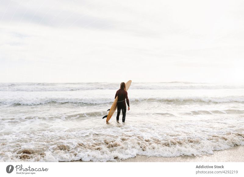 Anonymous surfer at the beach with surfboard man nature stand sunset wave outdoors wetsuit seacoast male sportsman surfing hobby ocean seaside calm catch water