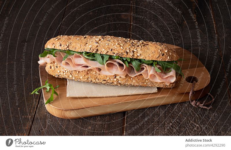 Mortadella sandwich on dark wooden table bun lettuce stuffed healthy brunch eat meat sandwich Rocket italian sandwich front closeup slices no people background