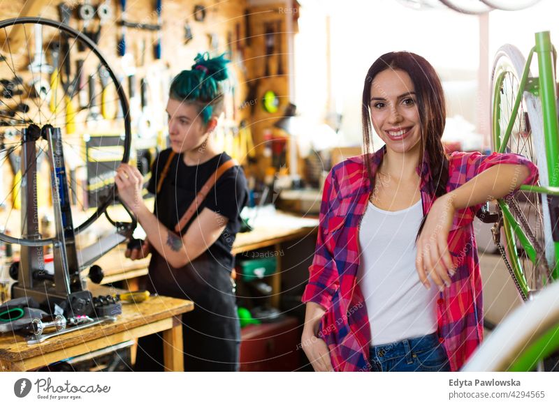 Two young women working in a bicycle repair shop sales clerk bicycle mechanic bicycling bike shop business retail helpful indoors woman female manager owner