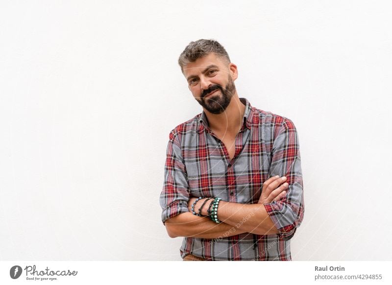 Portrait of smiling man standing with crossing arms looking to the camera on white background. person male isolated wall outdoor studio portrait adult confident