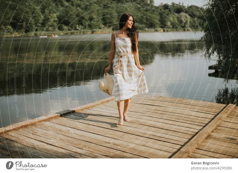 Relaxing young woman standing on wooden pier at the lake beautiful concept enjoy summer nature caucasian good casual female sunny dream person vacation leisure