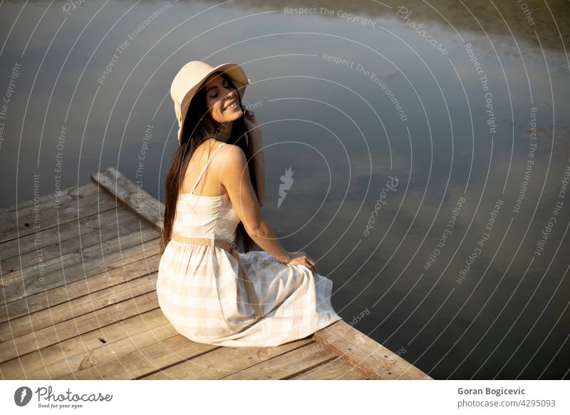 Relaxing young woman on wooden pier at the lake beautiful concept enjoy summer nature caucasian good casual female sunny dream person vacation leisure rest