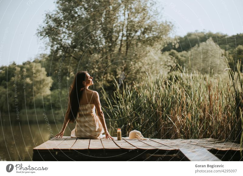 Relaxing young woman on wooden pier at the lake beautiful carefree casual caucasian coast concept day deck dream enjoy female good happy jetty leisure lifestyle