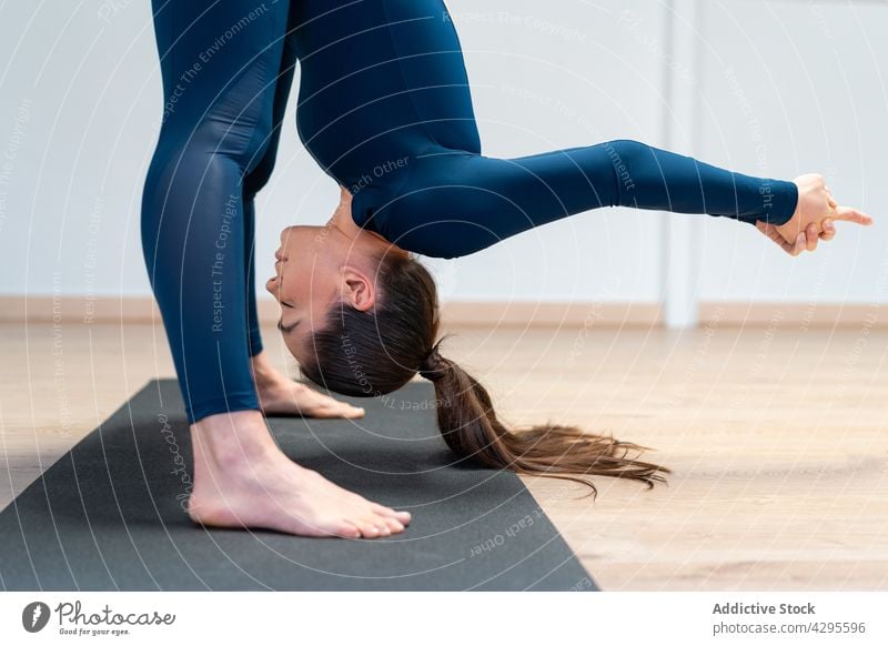 Fit woman doing forward bend yoga pose uttanasana stretch flexible stress relief position practice mindfulness female zen wellbeing wellness balance concentrate