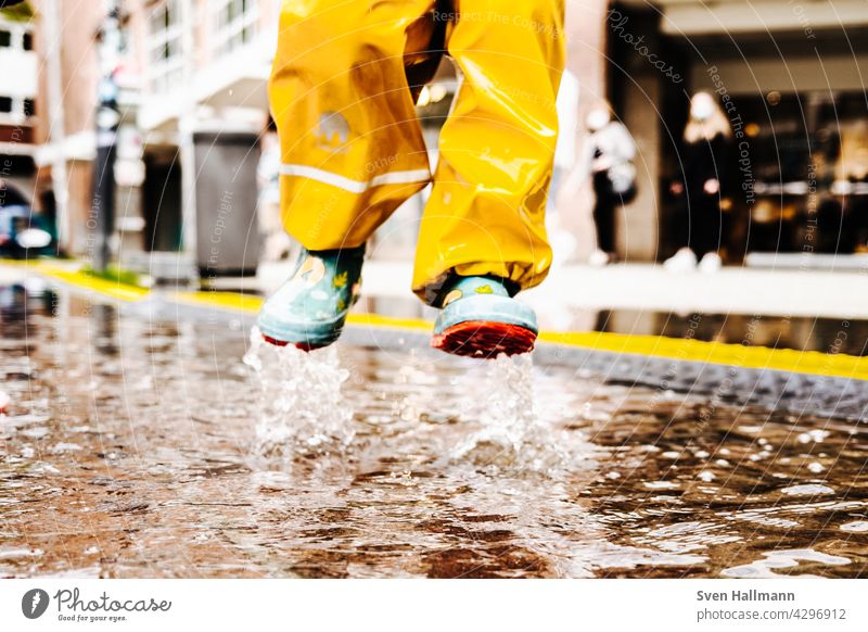 Child jumps happily into a puddle Puddle Water reflection Asphalt Street Wet Reflection Jump Rain Ground Bad weather Weather Clouds Playing feet Freedom Infancy