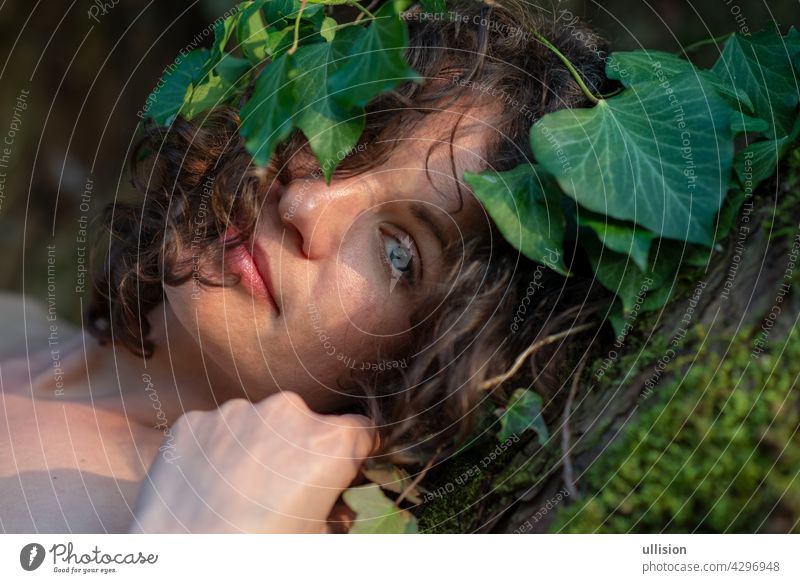 Gorgeous dark-haired young sexy woman stands comfortably happy in love of ivy wreathed in an old willow tree with fine shoulders and joy in smiles summer moss