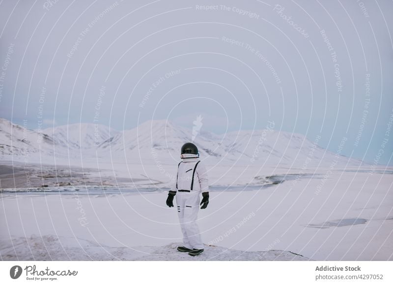 Spaceman in spacesuit in snowy mountains in winter spaceman highland astronaut traveler viewpoint cosmonaut rocky norway adventure stand scenery edge helmet