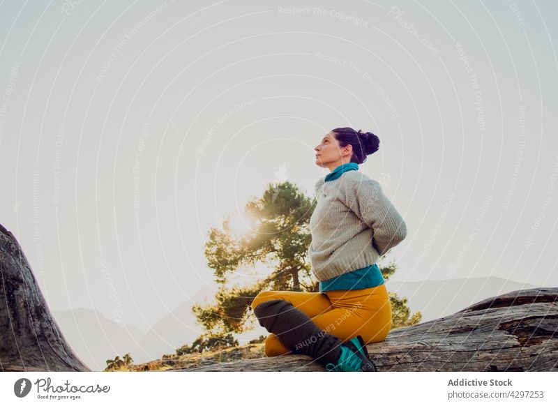 Woman practicing yoga in Cow face pose in highlands woman cow face pose practice mountain flexible harmony stretch zen female asana gomukhasana nature wellbeing