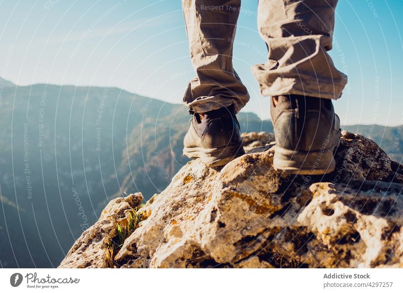 Crop traveler standing on rock in mountains trekking boot highland hill footwear adventure hike rocky wanderlust freedom explorer viewpoint hiker stone terrain