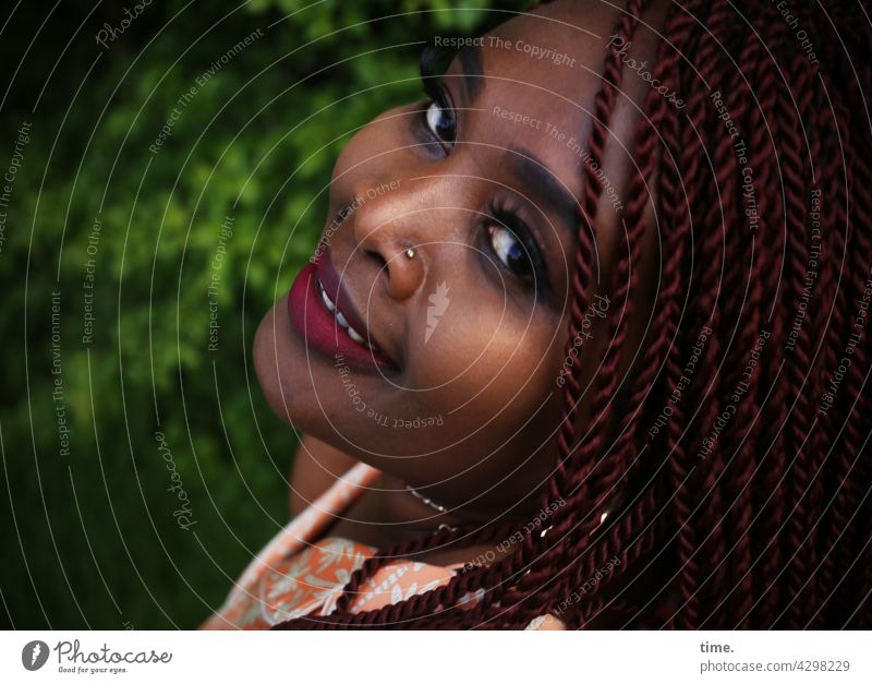 Gené - Woman with braids and friendly look over her shoulder feminine portrait Feminine Jewellery Looking hairstyle earring Close-up Smiling kind Half-profile