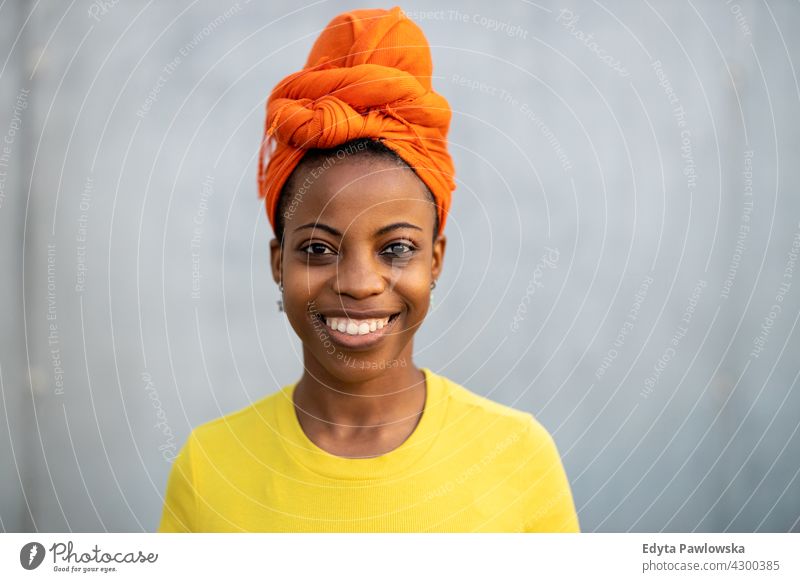 Beautiful young woman smiling in front of gray wall afro proud real people city life African american afro american student Black ethnicity sunny sunset outside