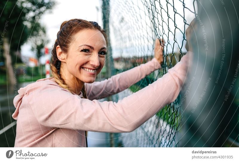 Sportswoman with boxer braids smiling leaning on a metal fence sportswoman looking camera active friendly female girl power happy hood portrait pretty stylish