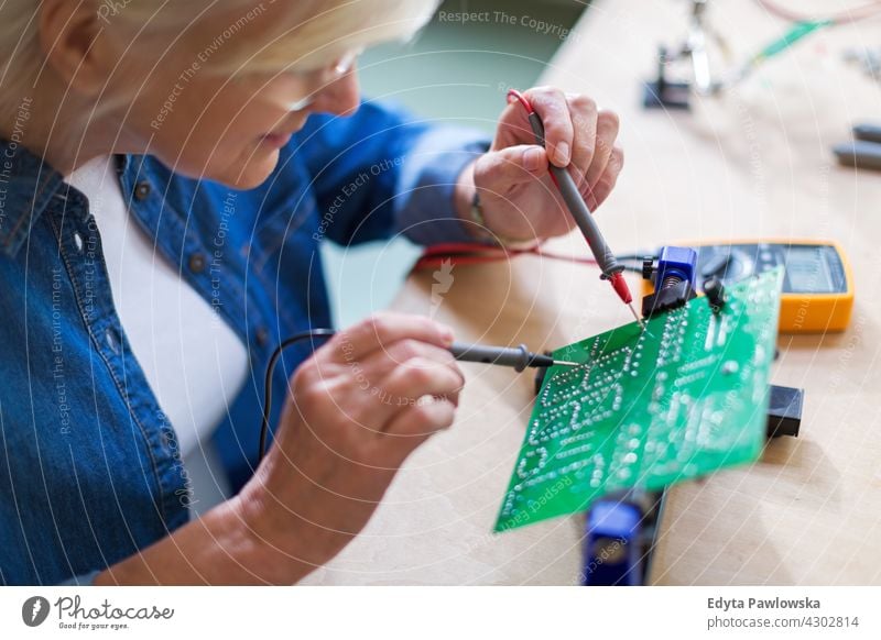 Senior woman in electronics workshop measurement current electricity Electrician Engineer Equipment Expertise Industry Job Repair soldering iron indoors female