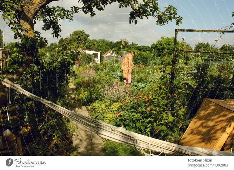 Young woman standing in the middle of her flower and vegetable garden Woman Garden self-sufficiency do gardening Relaxation Garden plot allotment Biological