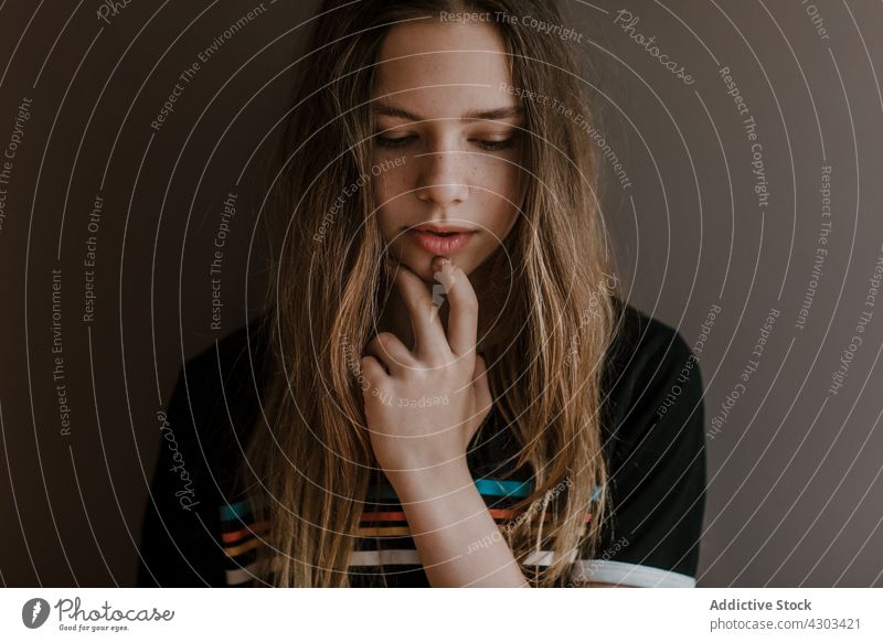 Pensive teenage girl looking down in studio portrait thoughtful charming natural think beauty serene long hair pensive carefree ponder style appearance