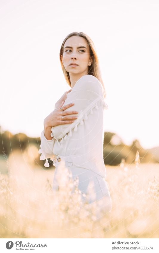 Thoughtful woman in white dress on sunny countryside field grass sunset romantic harmony freedom season tender meadow flower style rest gentle blond environment