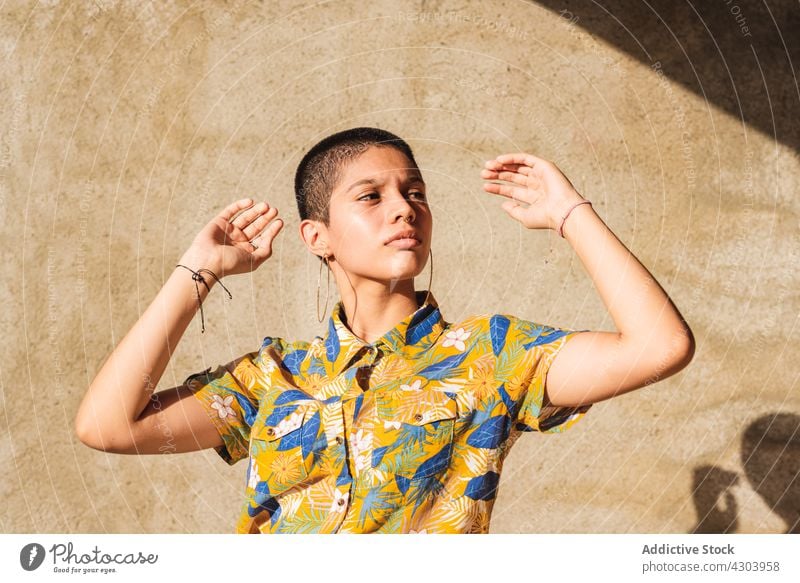 Ethnic woman in shirt with floral ornament in sunlight bisexual gender identity cool individuality vain portrait shadow contemplate contemporary generation