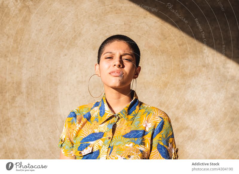 Ethnic woman in shirt with floral ornament in sunlight bisexual gender identity cool individuality vain portrait shadow contemplate contemporary generation