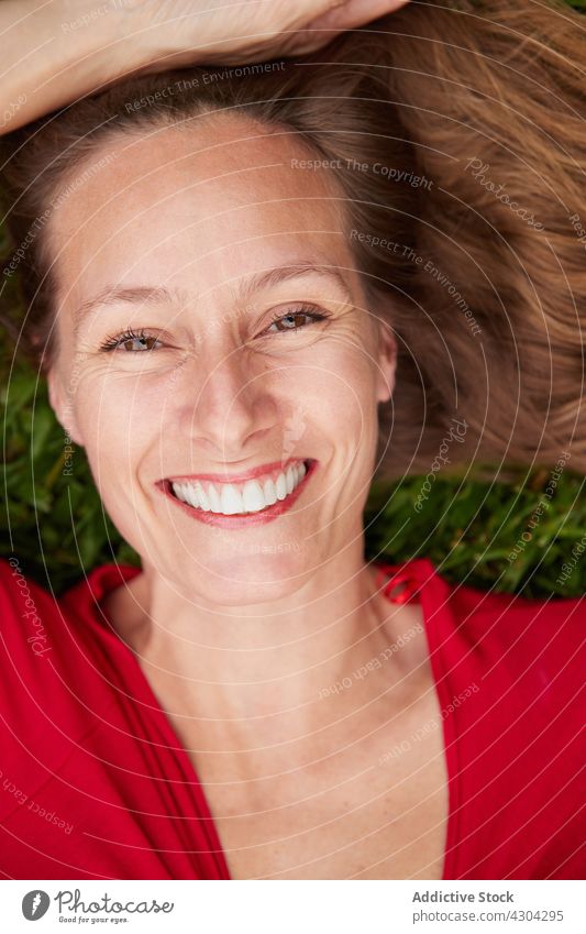 Woman dressed in red lying on the ground in a park with grass nature woman summer green young beautiful people female girl happiness happy meadow caucasian