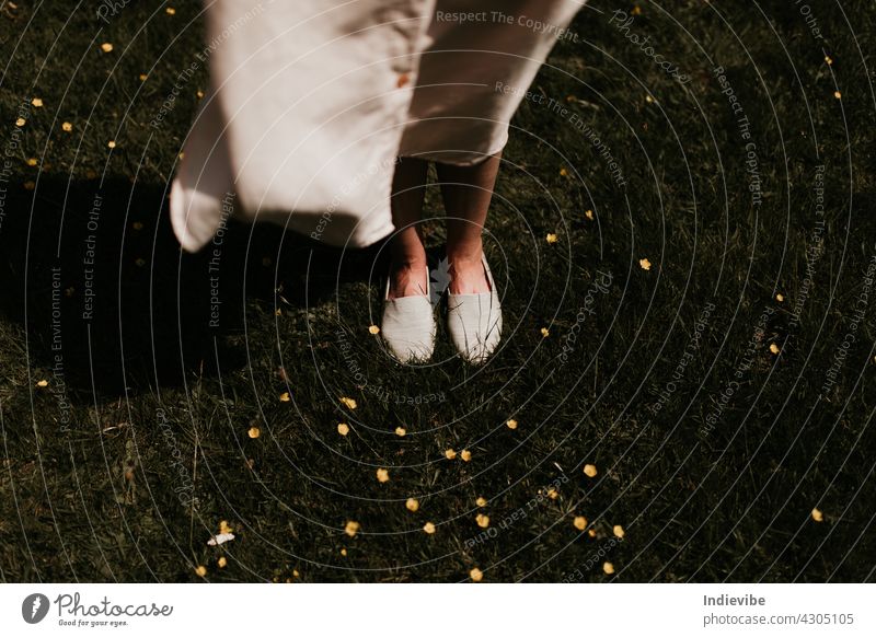 Woman feet with shoes on, on a field with yellow flowers and grass on a windy day barefoot blow face faceless forest fresh green health horizontal jogging leg