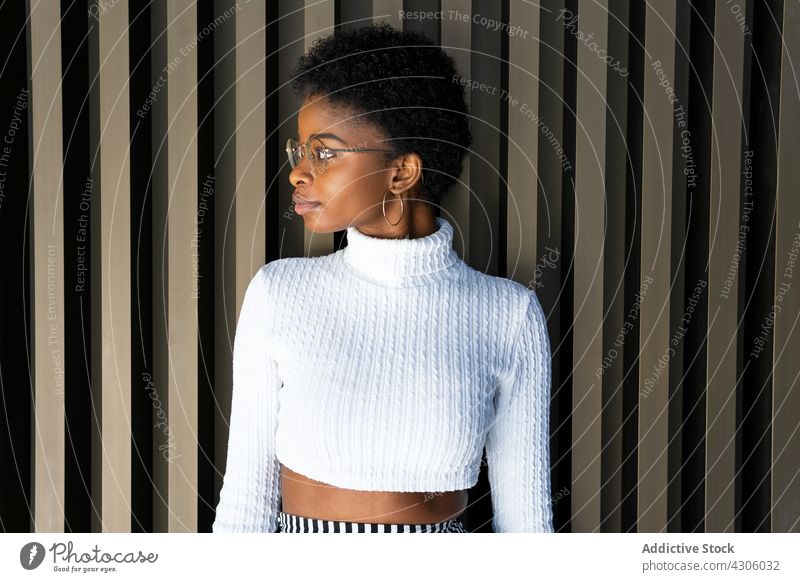 Young African American female near striped building wall woman smile happy style urban street city outfit fashion african american black ethnic young earring