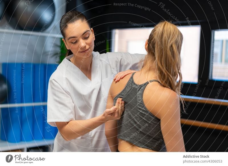 Physiotherapist fitting shoulder joint of woman osteopath pain patient physiotherapy clinic session rehabilitation injury women ache recovery client doctor