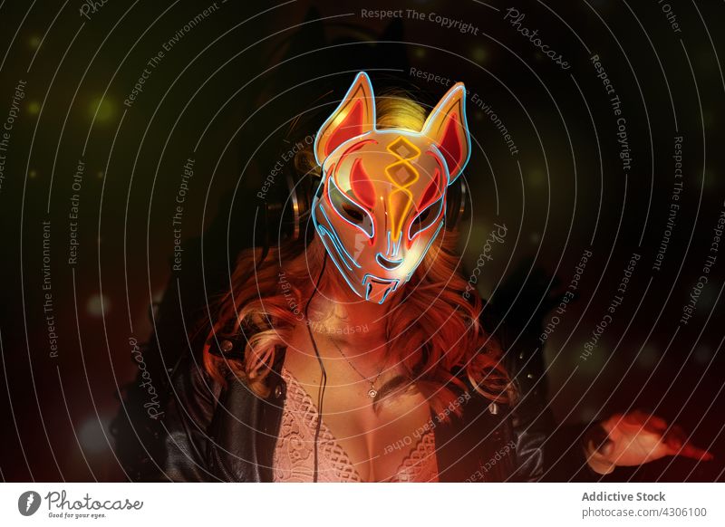 Female DJ in mask working in nightclub woman dj party creative music nightlife dark female young illuminate neon event ornament fox colorful festive entertain