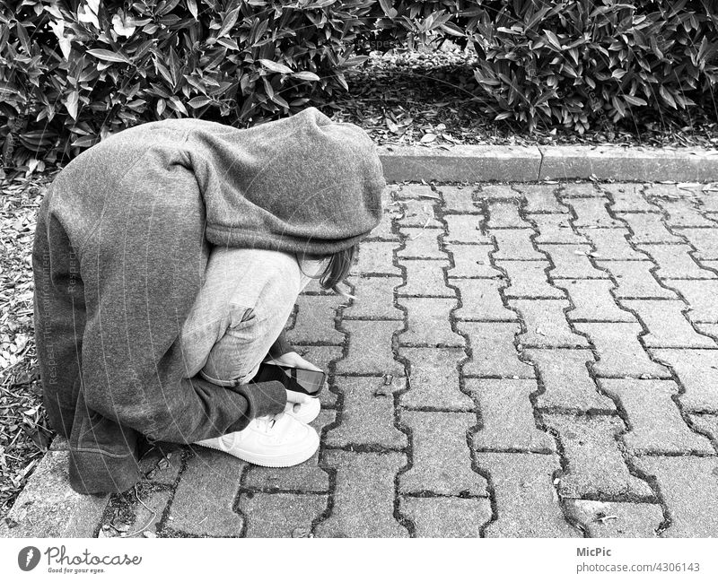 Communication- teenager sitting on the sidewalk with a cell phone in hand - black and white Cellphone smartphone Youth (Young adults) youth of today