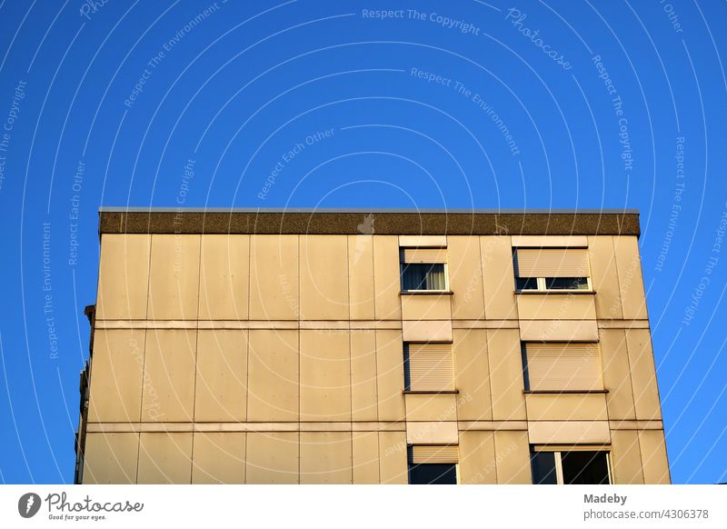 High-rise building in natural colours with roller shutters in front of the windows as sun protection against the blue sky in the light of the setting sun at the Hanauer Landstraße in the Ostend of Frankfurt am Main in Hesse