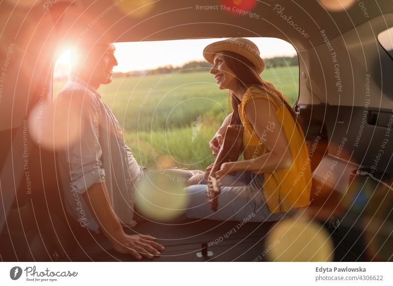 Young couple sitting in their car trunk and watching the sunset lights camper camping summer holiday sunrise sleeping vehicle road trip hippie meadow