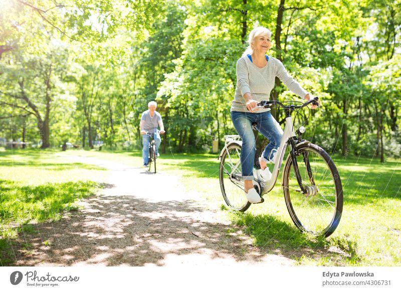 Senior Couple Riding Bikes In Park bicycle bike senior seniors pensioner pensioners casual outdoors day Caucasian happiness toothy smiling enjoying summer