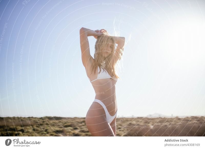 young woman standing at beach in a sunny day people cheerful sun tanning body female vacation blond beautiful ocean sea water fun relaxing accessory beauty hair