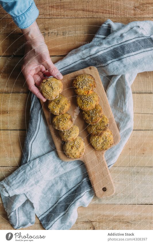 Crop person taking falafel from cutting board napkin table dish tradition wooden food sweet potato rustic fresh tasty delicious yummy gourmet organic healthy