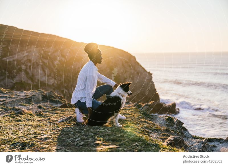 Black woman with dog on beach sunset together owner pet animal companion canine female sea purebred border collie ocean obedient loyal ethnic black