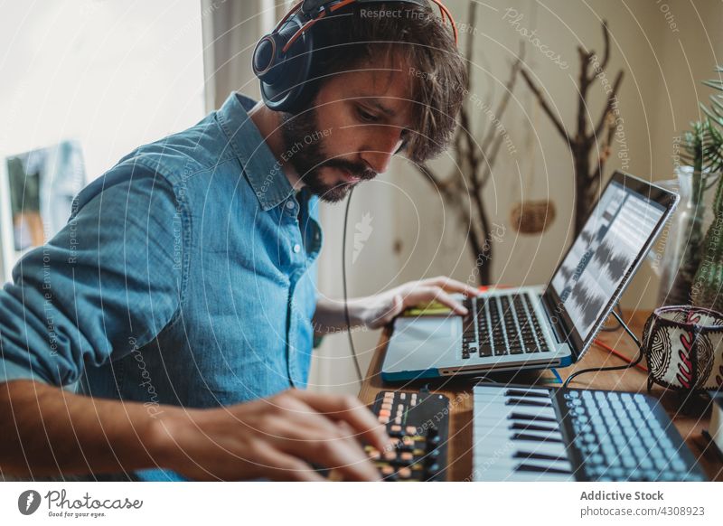 Musician using synthesizer and laptop at home musician headphones man young table studio device gadget equipment player recording room apartment leisure audio