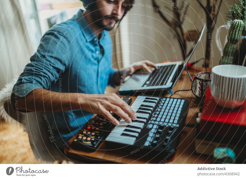 Musician using synthesizer and laptop at home musician headphones man young table studio device gadget equipment player recording room apartment leisure audio