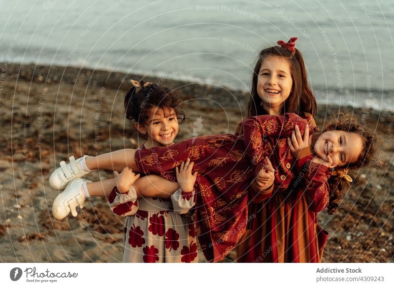 Cheerful siblings having fun on beach kid girl sister together sea children happy cute ethnic group friend best friend childhood cheerful joy little funny