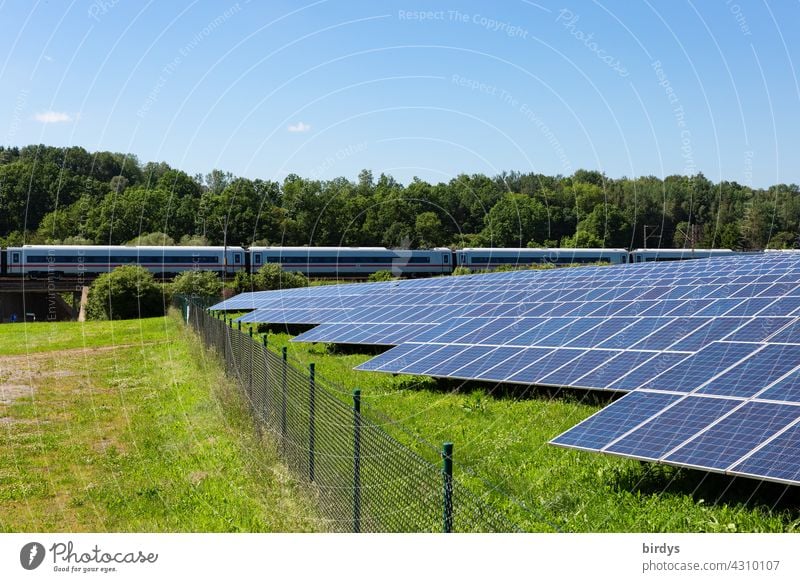 Photovoltaic - large-scale plant next to railway line with passing ICE. PV plant, solar energy photovoltaics photovoltaic system Outdoor facility