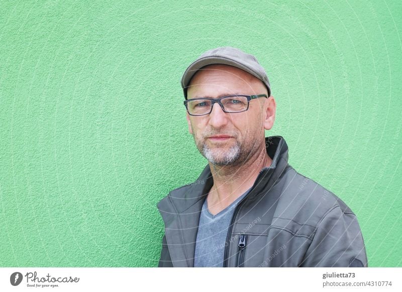 Portrait of a young senior male in front of green wall | AST 10 portrait Looking into the camera Central perspective Shallow depth of field Day