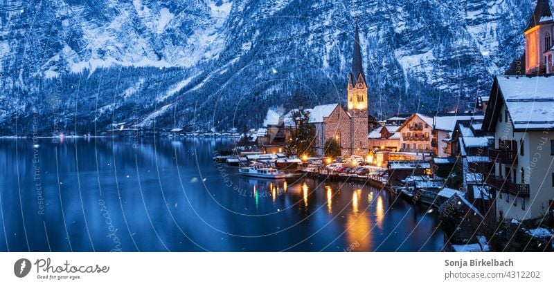 Hallstatt at the Hallstättersee with illuminated church on a winter evening, Austria hallstatt hallstättersee Tourist Attraction Winter Alps alpine village