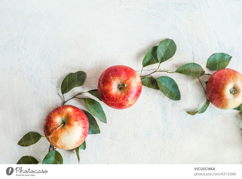 Red apples on white table with green leaves, top voew red raw color plant juicy ripe leaf fruit healthy food