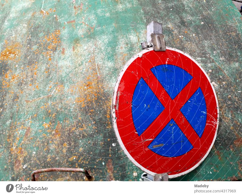 Traffic sign in strict prohibition to stop in front of a soiled green glass container in the city center of Offenbach am Main in Hesse, Germany No standing