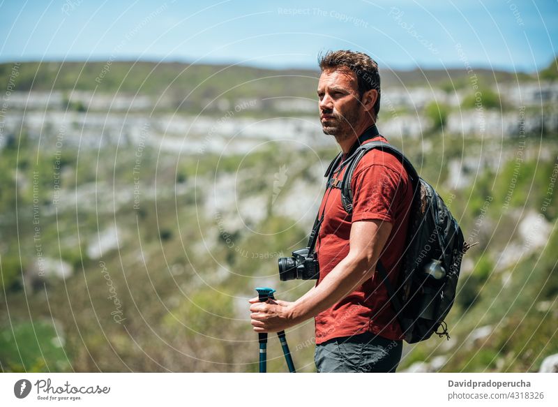 Traveler with backpack and photo camera on rocky slope hiker admire nature trekking pole wildlife landscape travel cliff tourism traveler editorial adventure