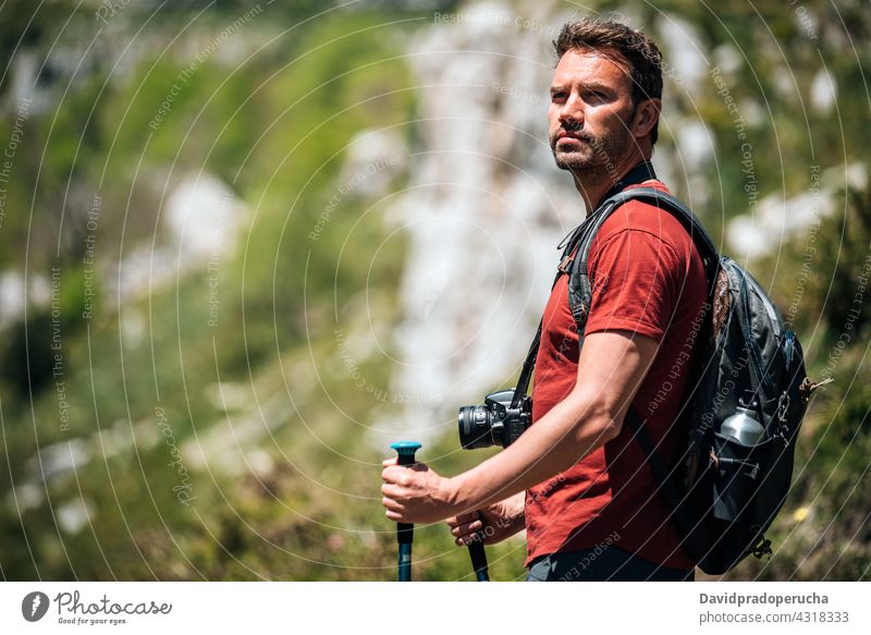 Traveler with backpack and photo camera on rocky slope hiker admire nature trekking pole wildlife landscape travel cliff tourism traveler editorial adventure