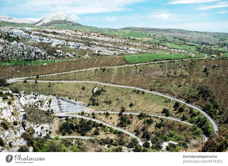 Winding roadway through green hills in highland serpentine curve slope mountain nature valley geology terrain asphalt landscape route vegetate hillside growth