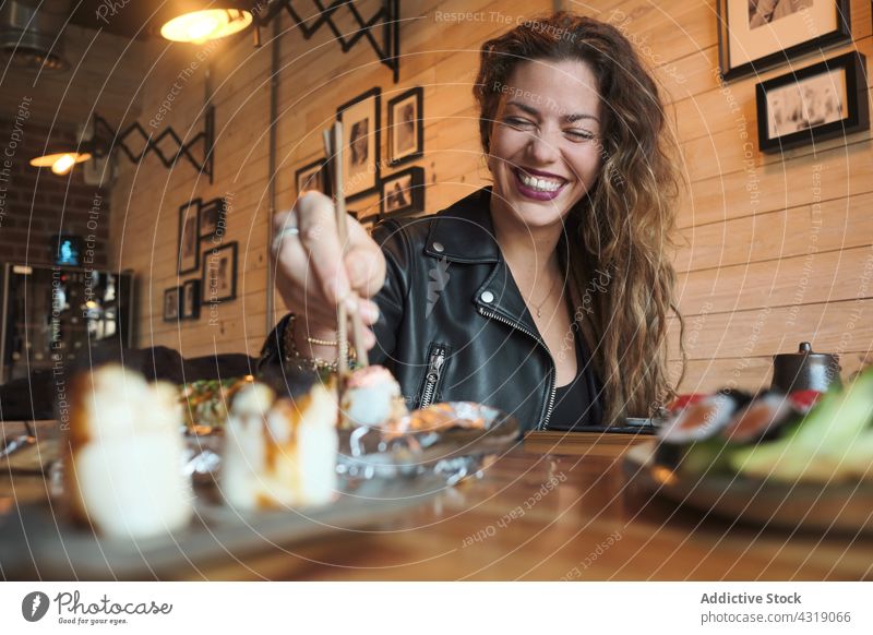 Cheerful woman eating sushi in Asian restaurant roll set asian food asian cuisine delicious tasty female table oriental yummy meal chopstick gourmet fresh