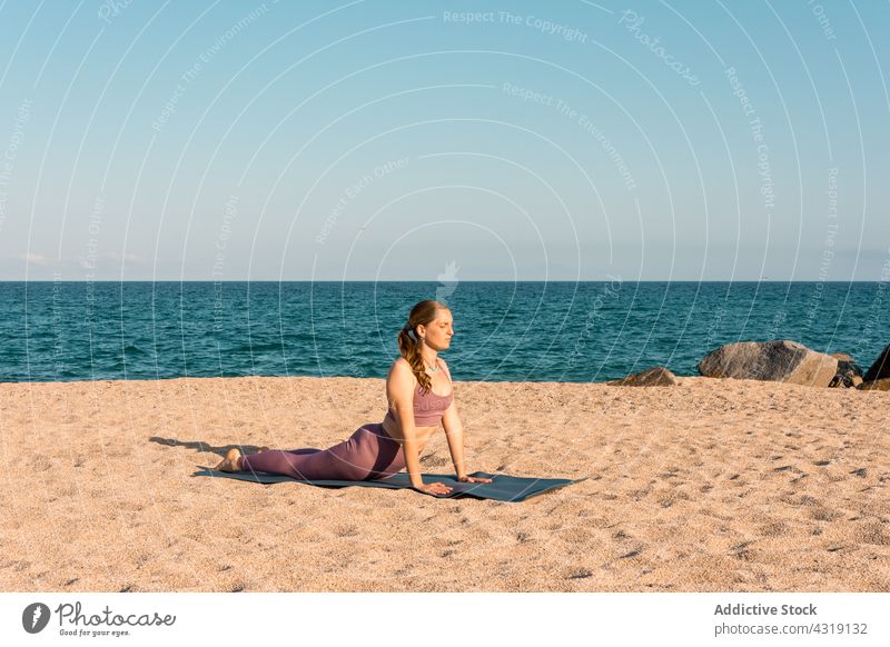 Woman practicing yoga in Cobra pose on seashore woman beach cobra pose stretch flexible asana harmony practice female healthy zen sand serene spirit body